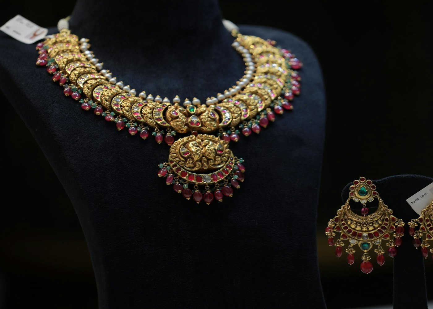A gold necklace and matching earrings laid out for a product photo