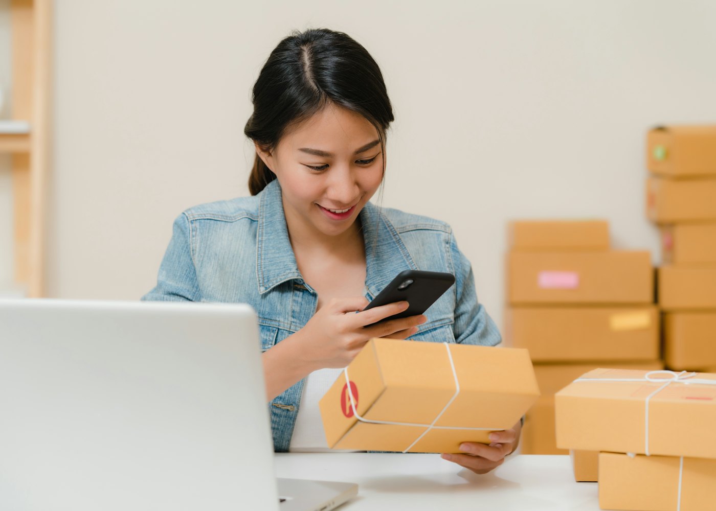 A seller checks orders on a phone next to packed boxes