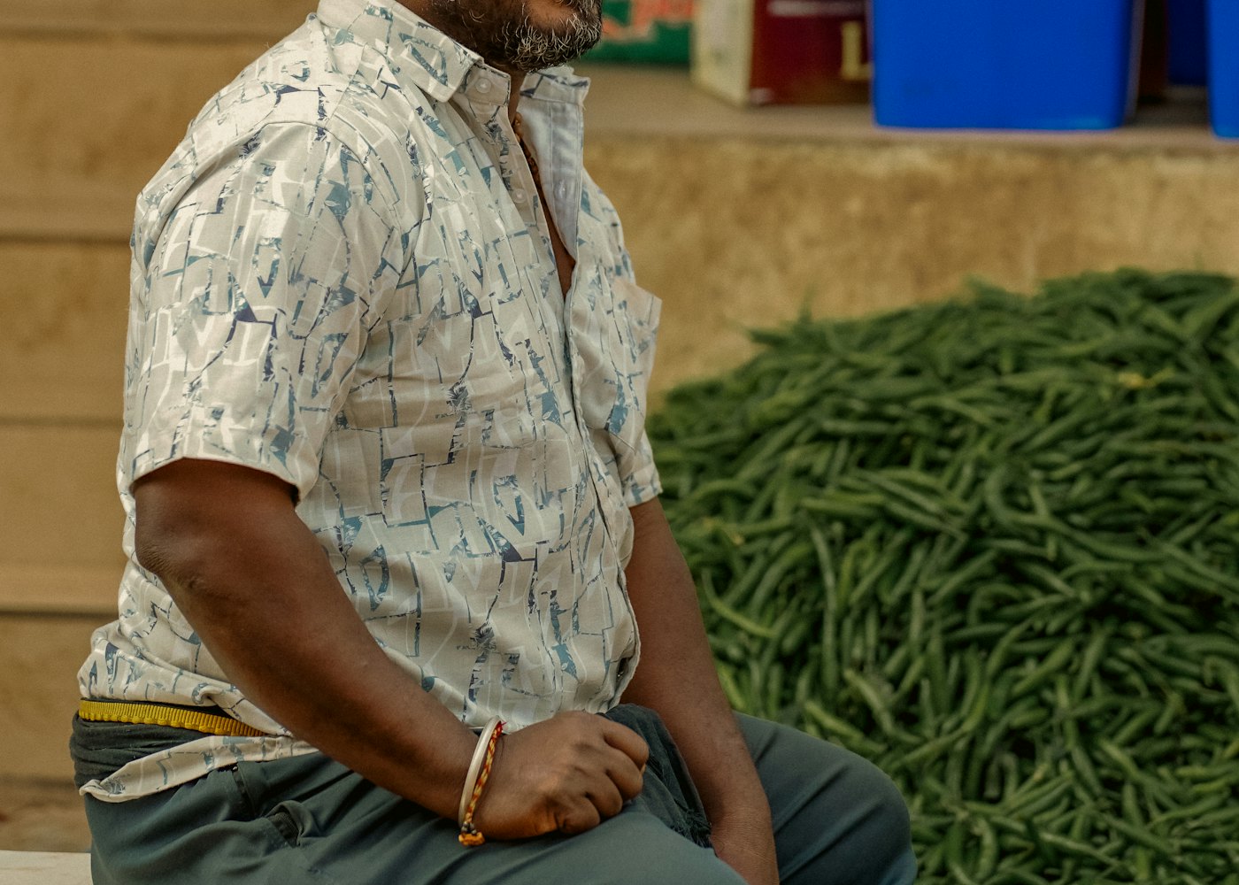 Smiling vegetable seller standing behind fresh produce at a market stall