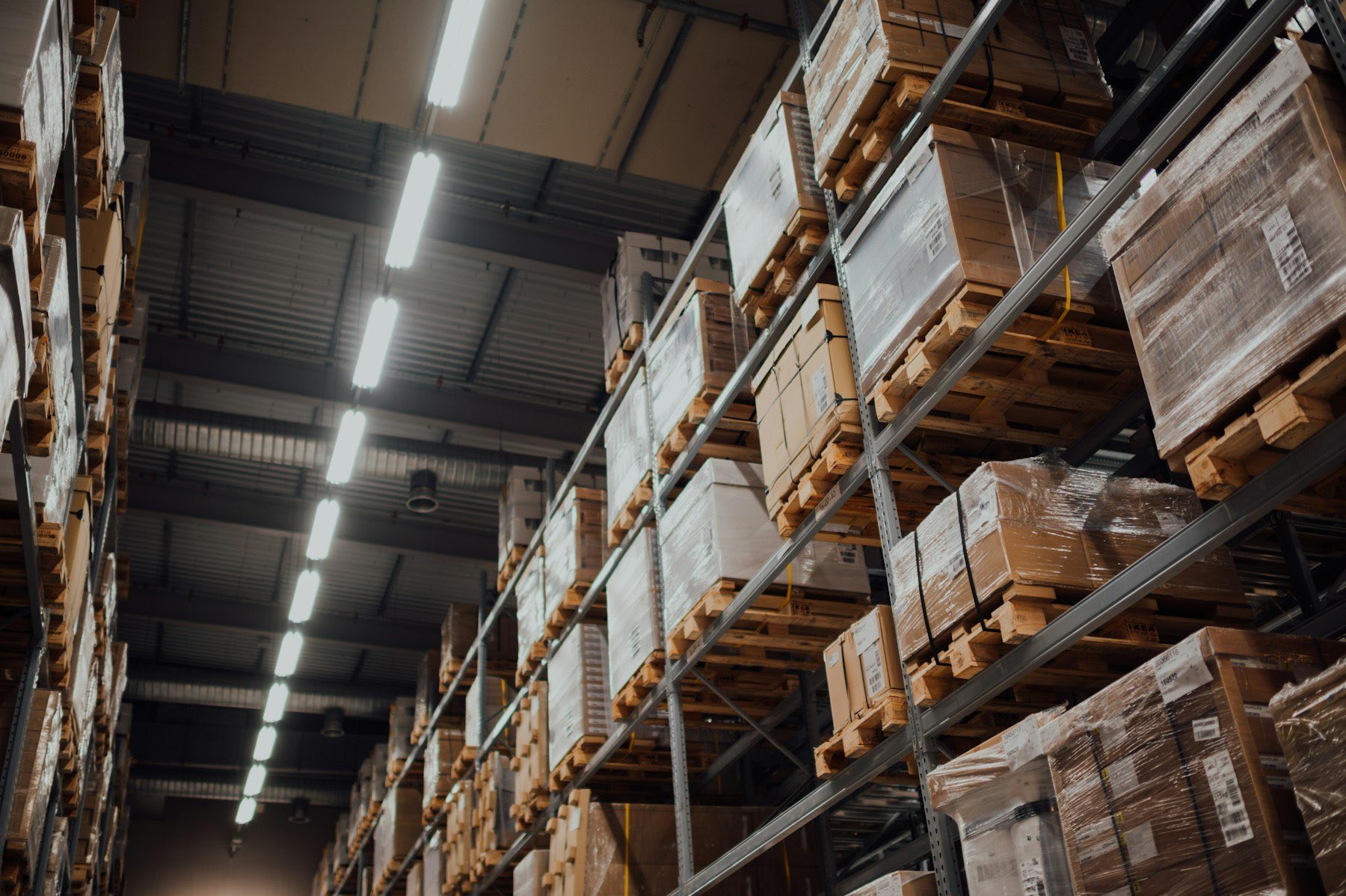 A warehouse aisle of tall racking stacked with boxes on pallets